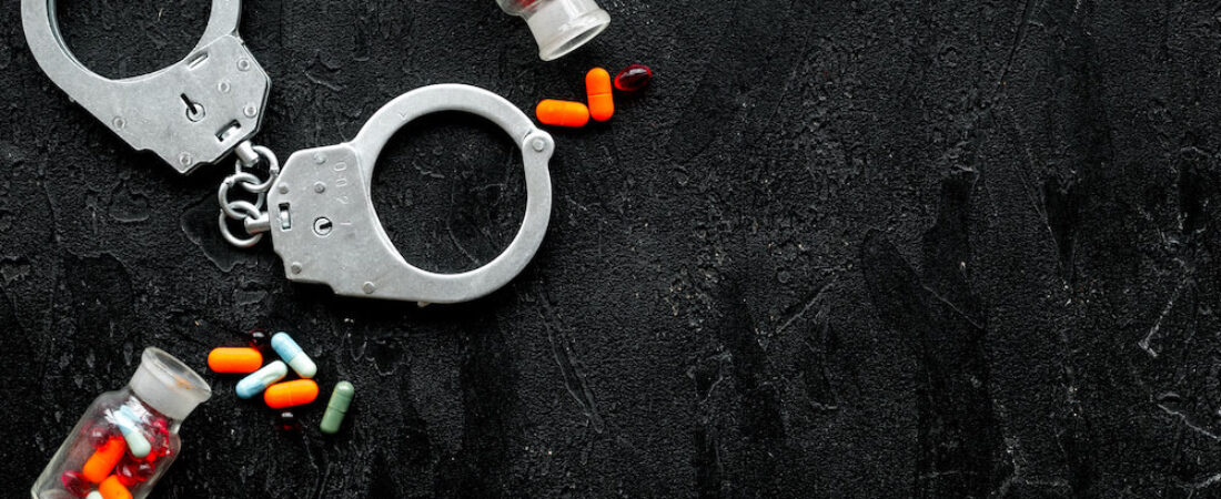 drugs that are illegal and handcuffs on a black background