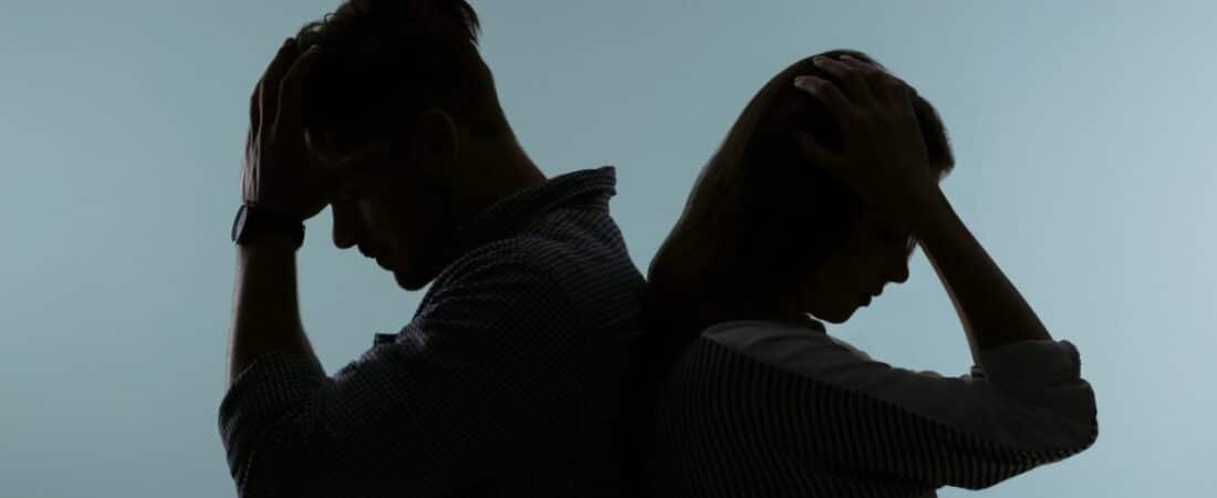 Silhouette of upset couple on color background.