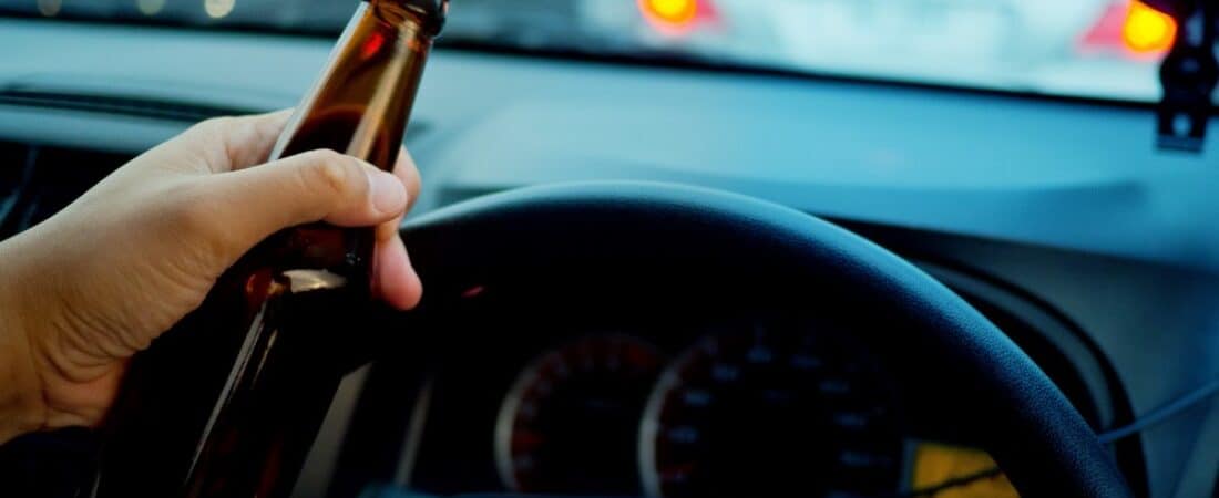 Man drinking a beer while driving car. Driving in a state of intoxication. Don't drink and drive concept.
